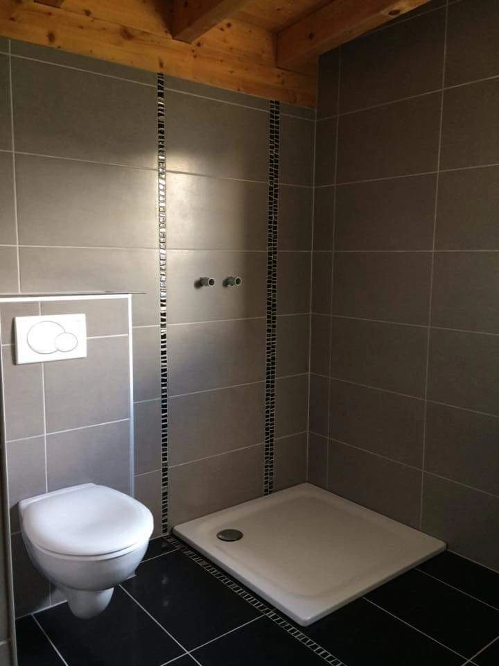 Salle de bains avec carrelage gris, douche et WC suspendu